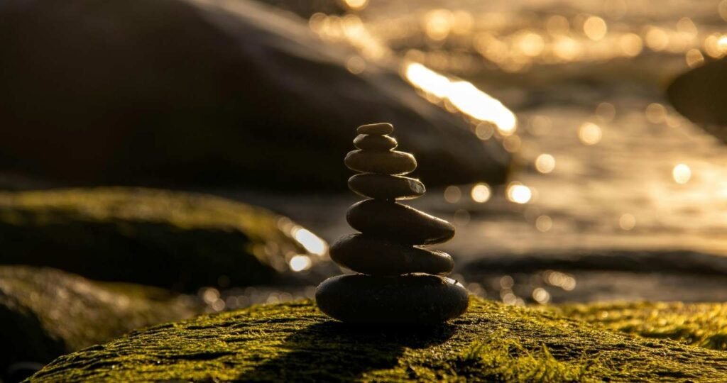 A balanced stone small tower in a serene natural background metaphorically representing the inner stillness that helps people avoid media manipulation.