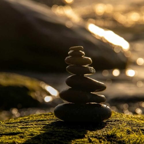 A balanced stone small tower in a serene natural background metaphorically representing the inner stillness that helps people avoid media manipulation.